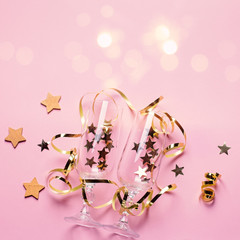 Christmas card with champagne glasses with confetti and streamers in pink and gold colors