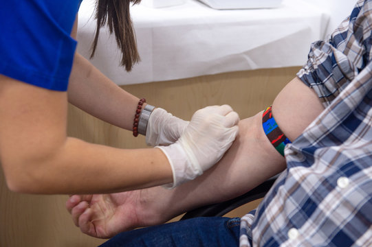 Close Up Of Nurse Disinfecting Male Arm Before Blood Test. Man Is Sitting On Chair Near Medical Set