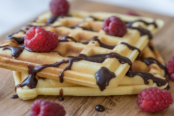 Two Viennese waffles with chocolate and berries on a wooden Board