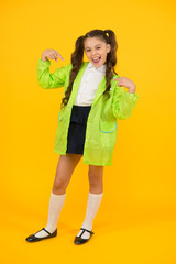 I am cool. Happy small child pointing fingers on yellow background. Small schoolchild on autumn day. Small girl back to school on rainy weather. Adorable small child in green raingear