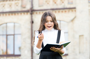 Keep writing. Happy little girl with textbook and writing pen outdoor. Small school child practising her writing skills. Improving your writing skills