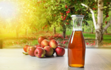apple juice in glass bottle  and apples on Woden Provence table on natural background 