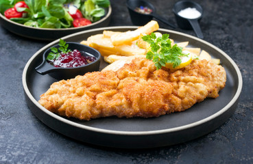 Deep fried Wiener schnitzel from veal topside with French fries and lettuce as closeup modern design plate