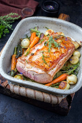 Traditional roasted dry aged veal tenderloin with carrots and onions offered as closeup in a saucepan