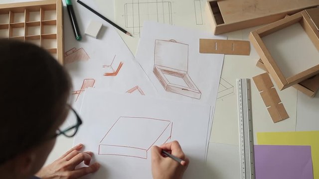 Designer draws a mockup for crafting cardboard box. Development of packaging design sketch.