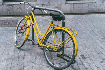 Yellow retro bicycle parked on the street.  Marble tiled  street pavement.