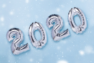 Silver balloons in the form of numbers 2020 on blue background. New year celebration. Air Balloons. Happy New Year concepts. Snow effects - Image