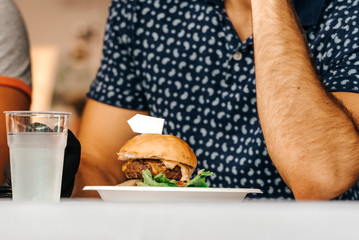 Burger on a plate, man in background.