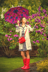 Beautiful woman with an umbrella in red rubber boots