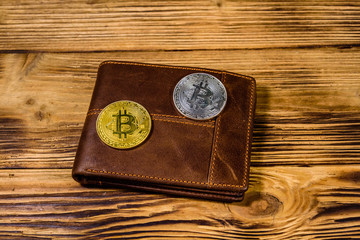 Brown leather wallet and bitcoins on the wooden background