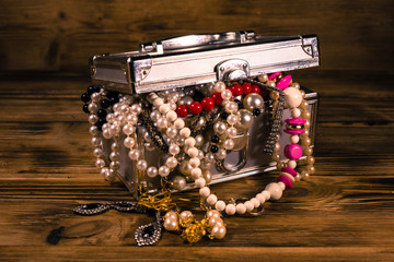 Aluminium case full of different jewelry on wooden table