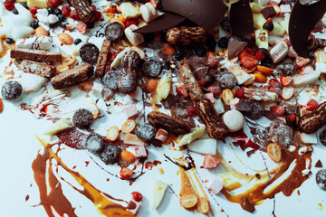 Mixed sweets, chocolates and fruits on white table.