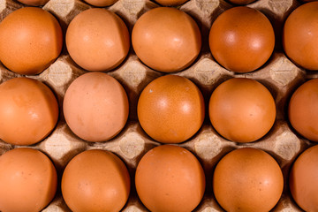 Pile of the hen eggs in paper tray on wooden table. Top view