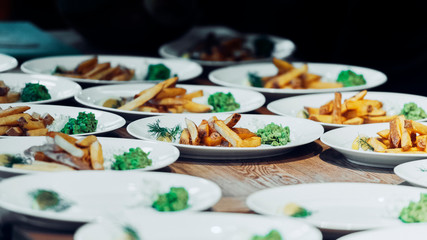 Obraz na płótnie Canvas French fries on multiple white plates with dark background.