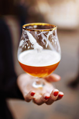 Women hand holding half empty glass of beer. (shallow focus image)