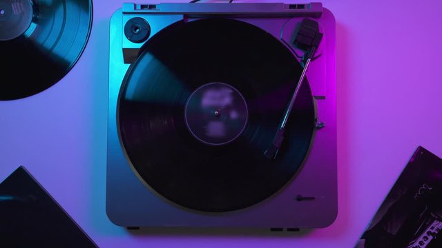 View from top: Vinyl record player on the table in blue and violet neon lights