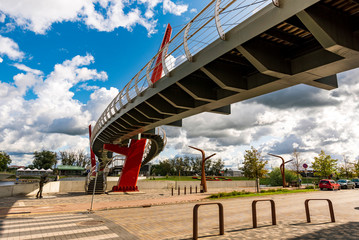 Modern Pedestrian Bridge Mitava over river Driksa in Jelgava, Latvia on a sunny day with blue sky.