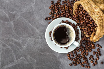Coffee cup with roasted beans on stone background.Cup of espresso and a small Breakfast croissants, Top view with copy space for your text