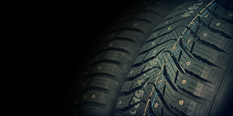 car tire with spikes macro fragment on dark background, wheel