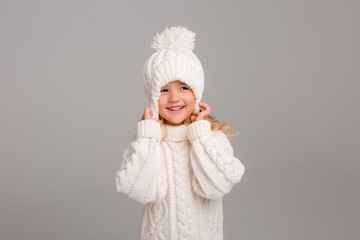 Winter clothes. Portrait of a little curly-haired girl in a knitted white winter hat. little blonde...