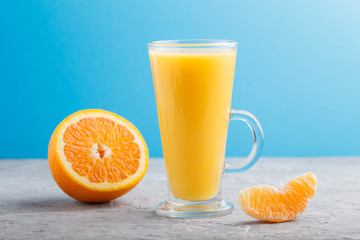 Glass of orange juice on a gray and blue background. Side view