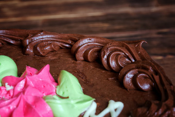 Example of laying out a sweet confectionery butter cream on a festive cake. Chocolate flavor. Wood background. Macro. Shallow depth of field