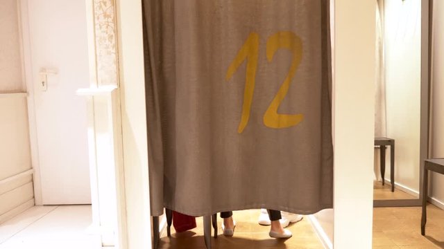 woman in a clothes fitting room. stylish bald woman comes out of the fitting room in leather leggings and a fashionable sweatshirt