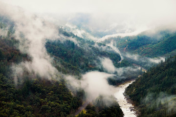 Mist, fog and storm clouds moving over railroad tracks and mountains in the Feather River Canyon of Butte County, California.