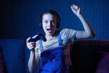 A girl gamer plays games with a gamepad, a joystick with emotions and creative light. Gaming, eSports