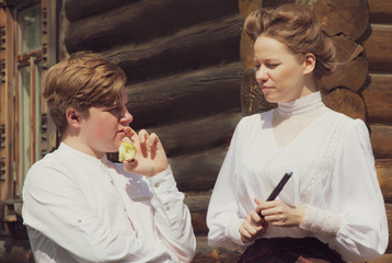A red-haired village boy and beautiful girl dressed in the style of the 19th century. Human relationships. Historical reenactment