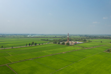 Oil and gas land drilling rig onshore in the middle of a rice field aerial view from a drone