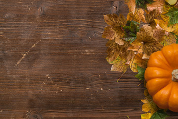 Autumn decoration with fallen leaves and pumpkin on wooden background