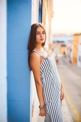 Fashion portrait of young elegant woman posing against the blue wall.