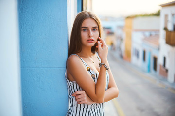 Fashion portrait of young elegant woman posing against the blue wall.