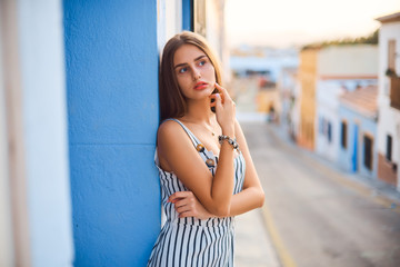 Fashion portrait of young elegant woman posing against the blue wall.