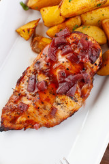 Close up of bbq grilled chicken breast with baked jacket potatoes and pickled cucumbers on a summer terrace