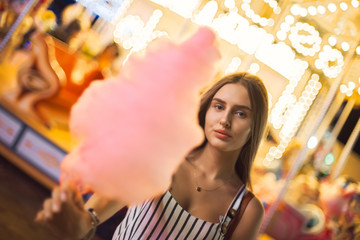 Pretty young woman against the background of magical bright carousel lights.