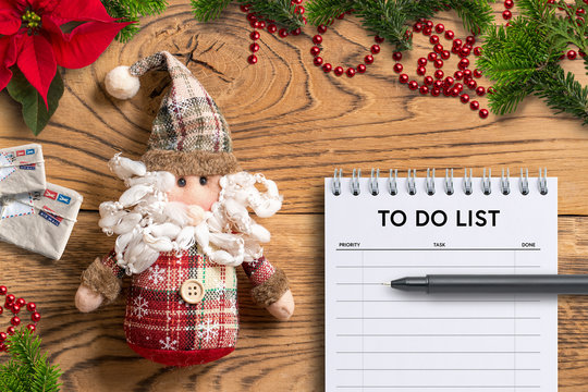 Santa Claus rag doll and to do list notepad on wooden background