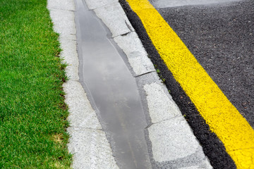 Obraz premium the current rainwater in the filled canal is a cement ditch of the drainage system on the side of a wet asphalt road after rain.