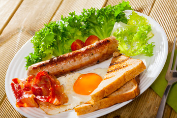 Fried egg with bacon, sausage and toasts