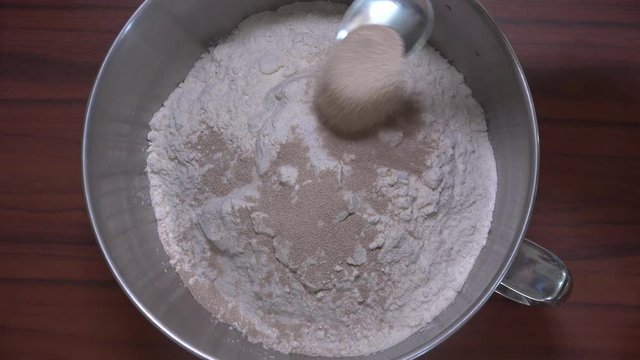 Adding two tablespoons of powdered yeast to bowl filled with white flour