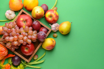 Box with many healthy vegetables and fruits on color background