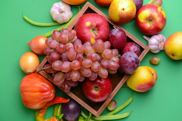 Fototapeta na wymiar Box with many healthy vegetables and fruits on color background