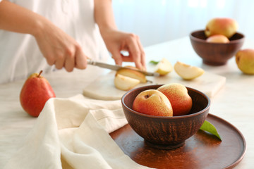 Woman cutting fresh pears at table