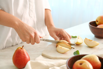 Obraz na płótnie Canvas Woman cutting fresh pears at table, closeup