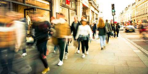 Motion blurred people on busy street of shops