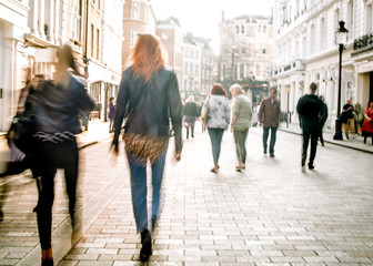 Motion blurred people on busy street of shops