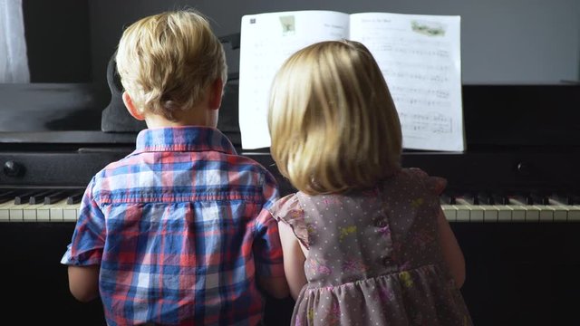 Young boy and girl play the piano together