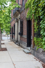 Sidewalk alongside residential building with bowed wrought iron grates over ground floor windows, vertical aspect