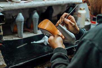 Hands of an old and experienced worker in the handmade footwear industry, performing cleaning and cosmetic tasks on products about to be finished.